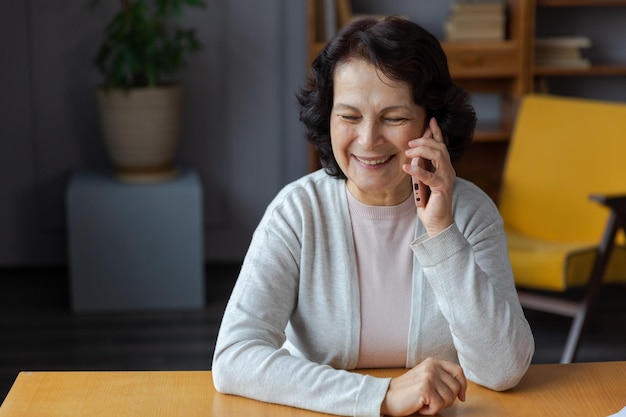 Szczęśliwa starsza kobieta w średnim wieku rozmawiająca na smartfonie z przyjaciółmi rodziny, starsza dojrzała dama z komórką