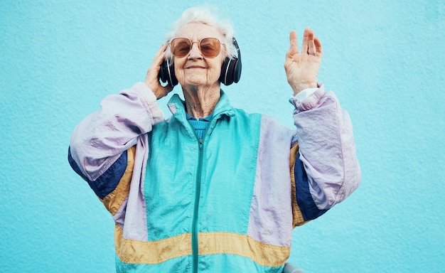 Szczęśliwa starsza osoba i kobieta z muzyką w słuchawkach do zabawy wellness i wypoczynku na emeryturze Miejski retro i funky starszy człowiek słuchający dobrego przesyłania strumieniowego na słuchawkach na niebieskiej ścianie