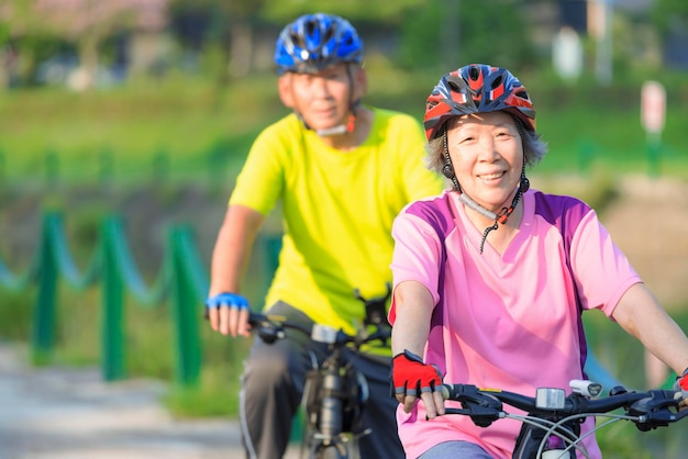 Szczęśliwa starsza para ćwiczy z bicyklami w parku