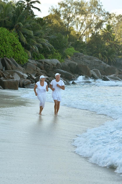Szczęśliwa starsza para spacerująca po tropikalnej plaży