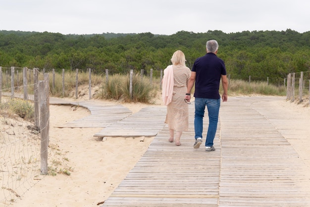 Szczęśliwa starsza para trzymająca się za ręce na letniej plaży