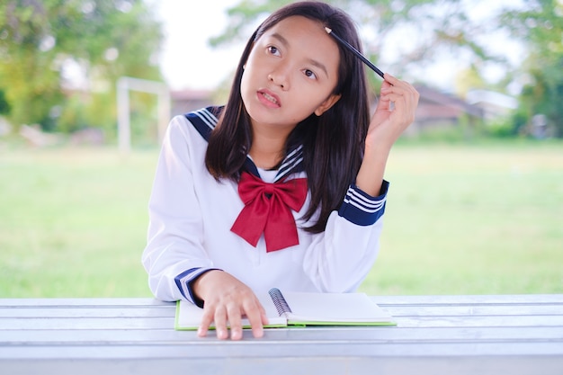 Szczęśliwa Studentka Z Książką Rozmieszczającą Na Zewnątrz W Szkole Azjatycka Dziewczyna