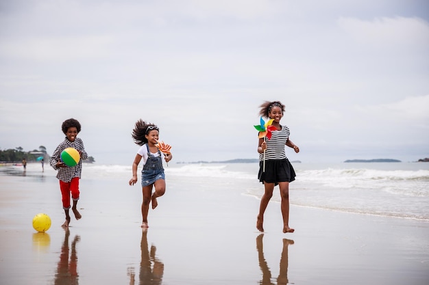 Szczęśliwa trójka afroamerykańskich dzieci bawiących się na tropikalnej plaży Koncepcja zróżnicowana etnicznie