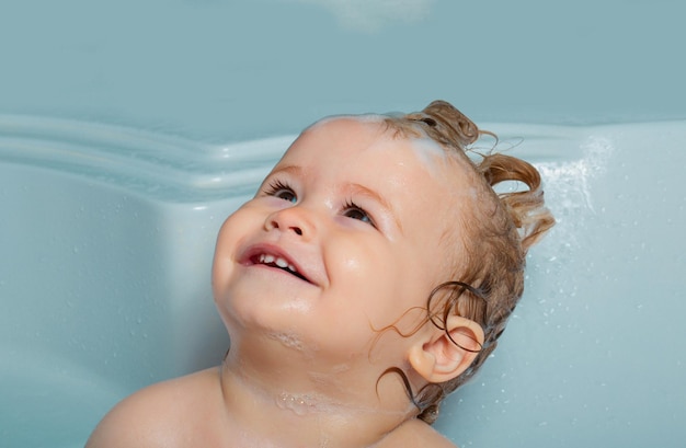Szczęśliwa twarz dziecka w kąpieli bąbelkowej zabawne szczęśliwe dziecko kąpiące się w wannie z wodą i pianką dzieci higiena
