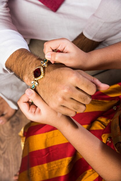 Szczęśliwa urocza mała indyjska dziewczyna świętująca festiwal Rakshabandhan lub Rakhi z wielkim bratem