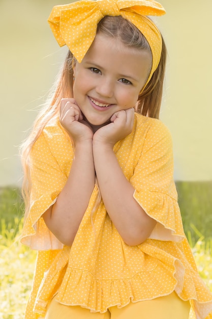 szczęśliwa uśmiechnięta blondynka z żółtą kokardą na głowie i sukienką