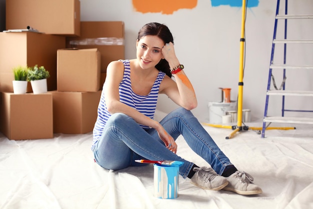 Szczęśliwa uśmiechnięta kobieta malująca wewnętrzną ścianę nowego domu szczęśliwa uśmiechnięta kobieta