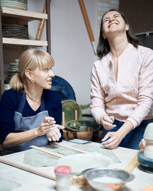 Szczęśliwa uśmiechnięta kobieta robi ceramicznemu garncarstwu.