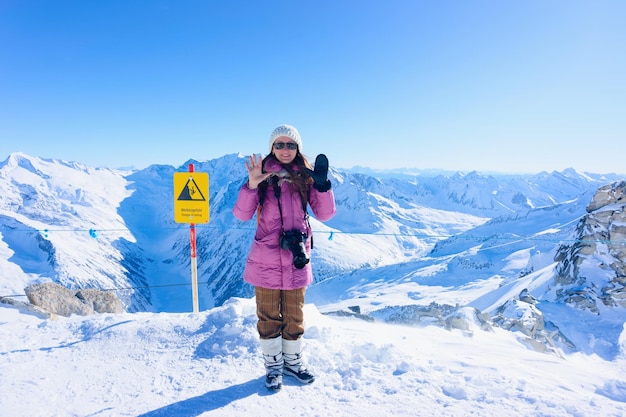 Szczęśliwa uśmiechnięta kobieta w jednej rękawiczce i okularach przeciwsłonecznych w ośrodku narciarskim na lodowcu Hintertux w Zillertal w Tyrolu w Austrii w zimie w Alpach. Alpejskie góry ze śniegiem. Pani i błękitne niebo i białe stoki.