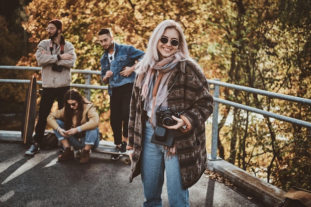 Szczęśliwa uśmiechnięta kobieta z aparatem fotograficznym cieszy się jasny jesienny dzień w parku.