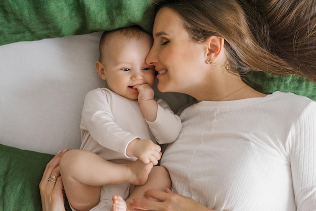 Szczęśliwa uśmiechnięta matka i dziecko leżące na łóżku w domu na łóżku widok z góry matka całuje syna