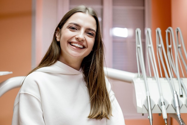 Szczęśliwa Uśmiechnięta Młoda Kobieta Z śnieżnobiałym Uśmiechem W Recepcji Dentysty Koncepcja Opieki Stomatologicznej