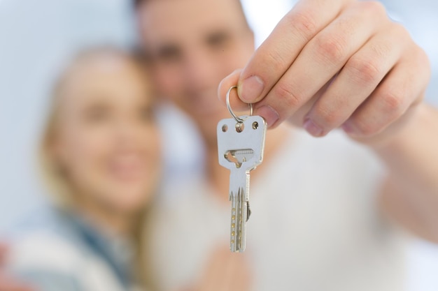 Szczęśliwa uśmiechnięta młoda para przytulająca się, pokazująca klucze do ich nowego domu