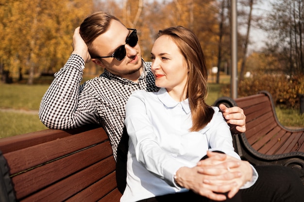 Szczęśliwa uśmiechnięta para na ławce w parku jesienią słoneczny dzień