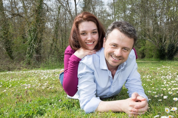 Szczęśliwa uśmiechnięta para razem relaksuje się na zielonej trawie w parku