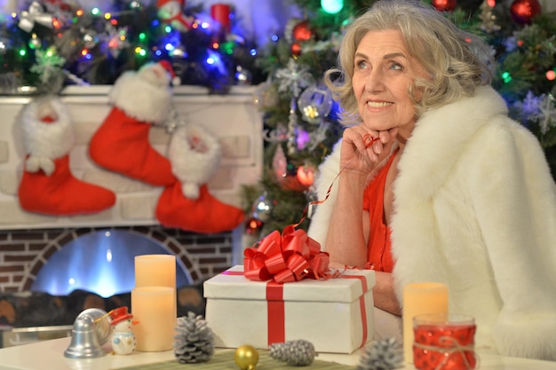 Szczęśliwa uśmiechnięta starsza kobieta z prezentem na Boże Narodzenie