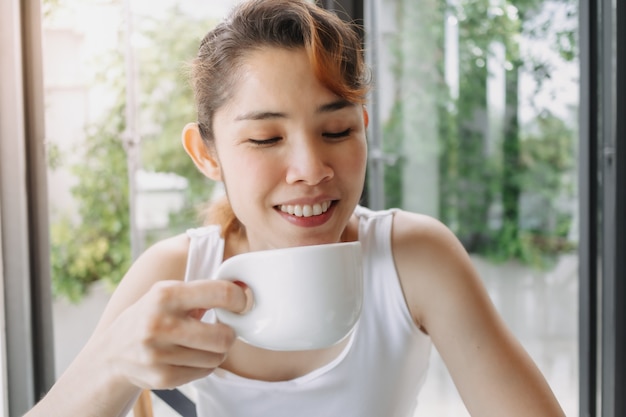 Szczęśliwa uśmiechnięta twarz kobiety podziwia moment przy filiżance kawy