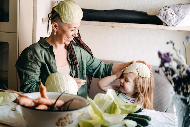 Szczęśliwa wegańska rodzinna mama i córeczka gotują razem i bawią się w kuchni rodzinnego gotowania