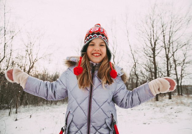 Szczęśliwa wesoła dziewczynka zabawy w lesie w zimowy dzień. dziecko bawi się śniegiem.