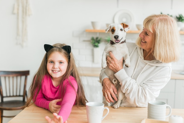 Szczęśliwa wnuczka i babcia w kuchni z psem jack russell terrierem babcią i