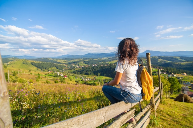 Szczęśliwa wspaniała dziewczyna cieszyć się widokiem na wzgórza siedząc w polu kwiatowym na wzgórzu z zapierającym dech w piersiach krajobrazem przyrody.