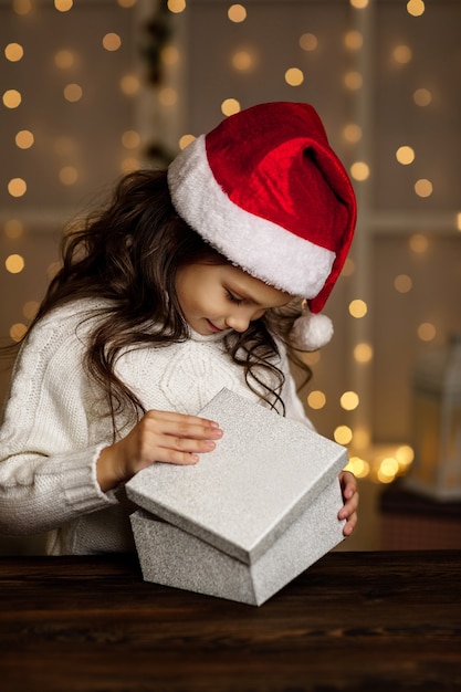 Szczęśliwa Zaskoczona Mała Dziewczynka W Santa Hat Otwierając Srebrne Pudełko