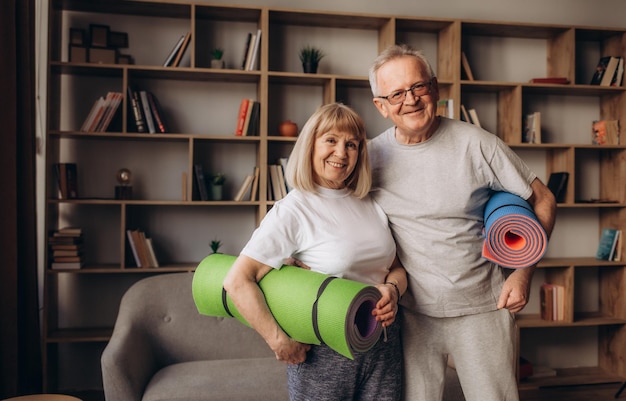 Szczęśliwa, zdrowa, starsza para seniorów z lat 60., ciesząca się treningiem sportowym fitness razem w mieszkaniu