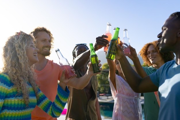 Szczęśliwa, zróżnicowana grupa przyjaciół imprezujących, pijących piwo i wznoszących tosty w ogrodzie. Styl życia, przyjaźń i impreza, lato, słońce, bez zmian.