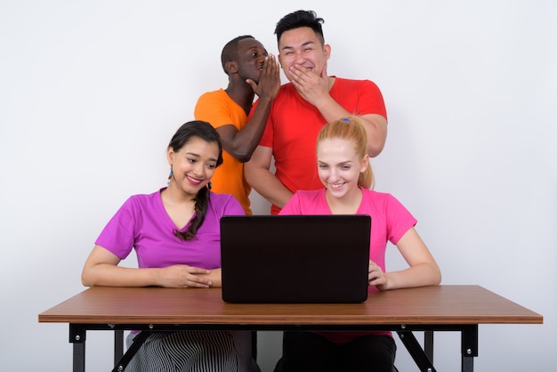 Szczęśliwa zróżnicowana grupa wieloetnicznych przyjaciół smiliingng podczas korzystania z laptopa