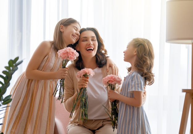 Szczęśliwe córki dzieci gratulują mamie i dają jej kwiaty