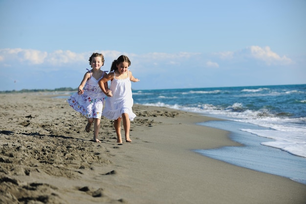 szczęśliwe dwie małe dziewczynki bawią się i bawią na pięknej plaży, uciekając przed radością