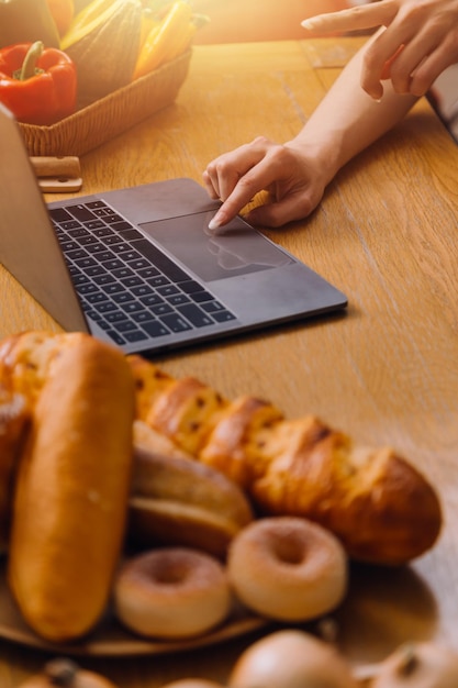 Szczęśliwe dwie młode kobiety patrzące na laptopa podczas wspólnego gotowania w pokoju kuchennym w domu Dwie młode, zróżnicowane lesbijki spędzające razem czas Koncepcja LGBT i tożsamości płciowej