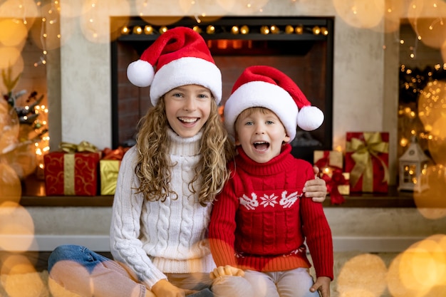 Szczęśliwe dzieci kominku na Boże Narodzenie. Dzieci bawią się w domu.
