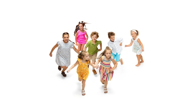 Szczęśliwe dzieci, małe i emocjonalne kaukaski dzieci skaczą i biegają na białym tle. Wygląda szczęśliwie, wesoło, szczerze. Miejsce na reklamę. Dzieciństwo, edukacja, koncepcja szczęścia.