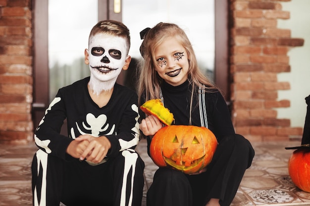 Zdjęcie szczęśliwe dzieci świętują halloween na ulicy w pobliżu domu w kostiumach i makijażu