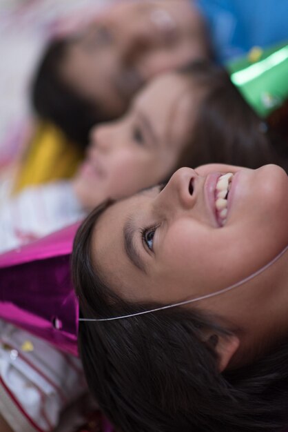 Szczęśliwe dzieci świętujące imprezę z dmuchaniem konfetti leżąc na podłodze