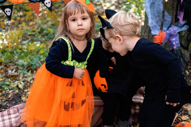 Zdjęcie szczęśliwe dzieci w kostiumach halloween bawiące się dekoracjami halloween na zewnątrz