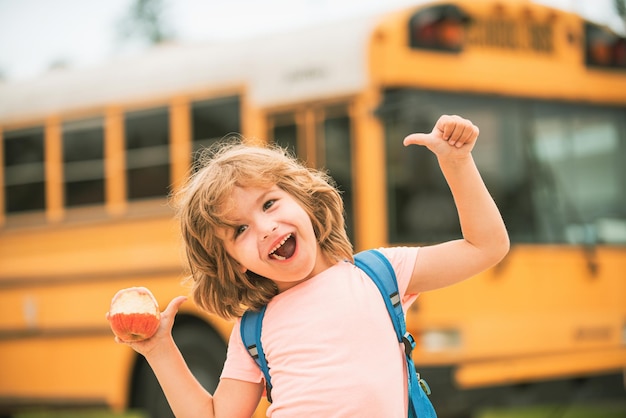 Szczęśliwe dzieci w wieku szkolnym w szkolnym autobusie Dziecko kciuki do góry uśmiechnięte i szczęśliwe