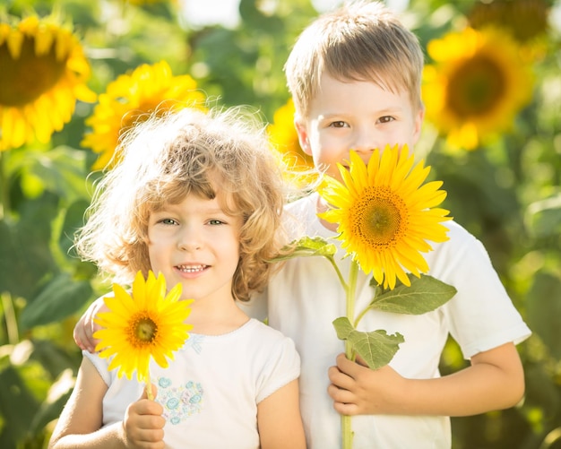 Szczęśliwe dzieci ze słonecznikiem bawiące się na wiosennym polu