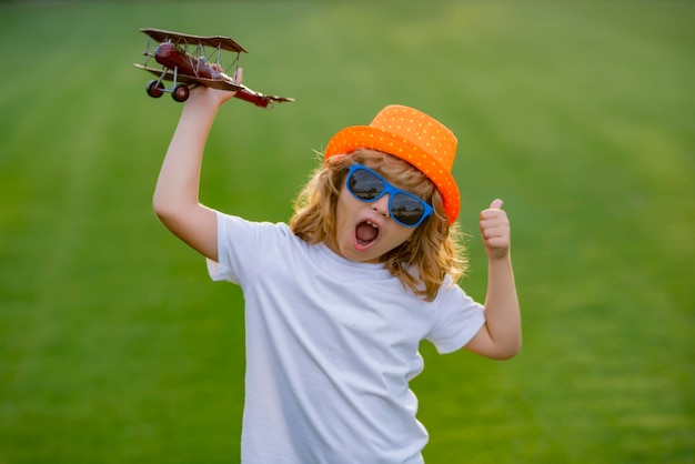 Szczęśliwe dzieciństwo Letni portret szczęśliwego uroczego dziecka Cieszy się życiem i przyrodą Mały chłopiec bawi się i marzy o lataniu Koncepcja dzieciństwa Mały ładny chłopiec bawi się skrzydłami samolotu zabawek
