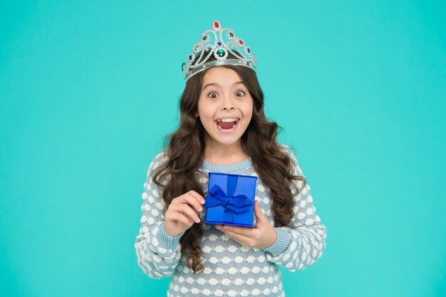Szczęśliwe dzieciństwo Skoncentruj się na urodzie Dziewczyna nosi koronę Księżniczka maniery Dziewczyna w koronie trzyma pudełko na prezent urodzinowy Odnosząca sukcesy dziewczyna nosi dziecko luksusowa korona Drogie luksusowe prezenty