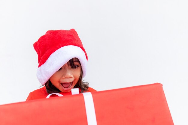 Szczęśliwe dziecko azjatyckie w Santa czerwony kapelusz gospodarstwa prezenty świąteczne. Boże Narodzenie time.on białym tle.