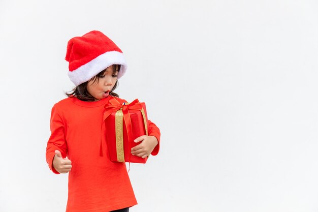 Szczęśliwe dziecko azjatyckie w Santa czerwony kapelusz gospodarstwa prezenty świąteczne. Boże Narodzenie time.on białym tle.
