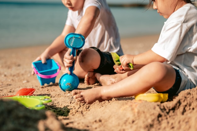 Szczęśliwe dziecko bawiące się piaskiem podczas letnich wakacji na plażyKoncepcja podróży i wakacji