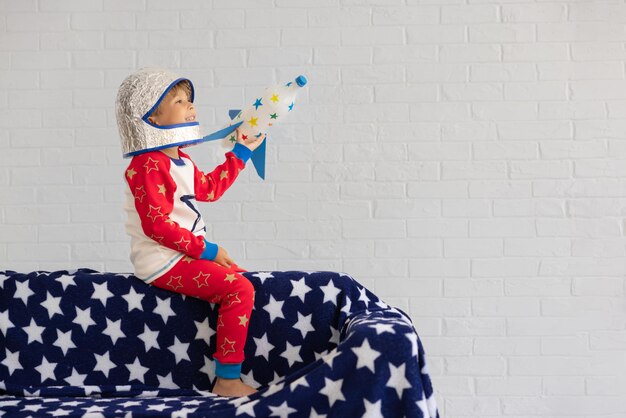 Szczęśliwe dziecko bawiące się rakietą-zabawką na tle ceglanego muru