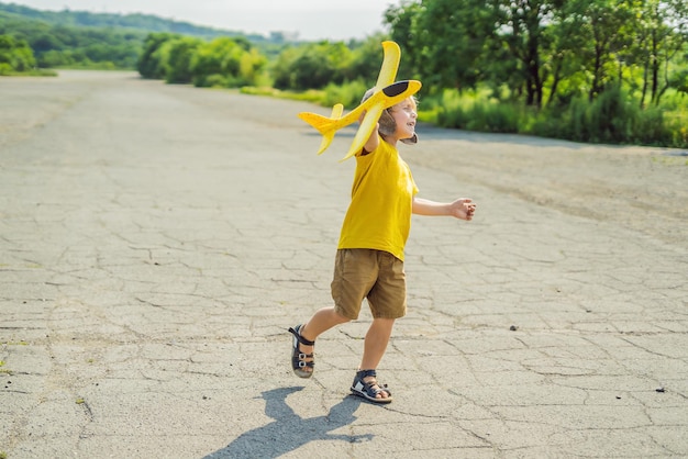Szczęśliwe dziecko bawiące się samolocikiem na tle starego pasa startowego Podróżowanie z koncepcją dzieci