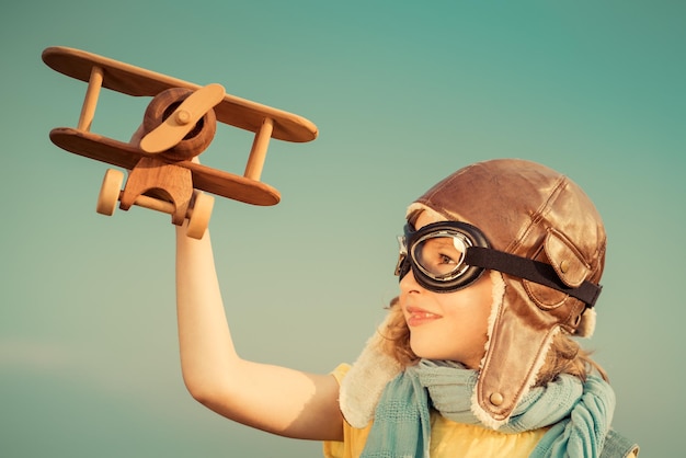 Szczęśliwe dziecko bawiące się samolocikiem na zewnątrz Dziecko bawiące się na tle letniego nieba Koncepcja podróży i wyobraźni