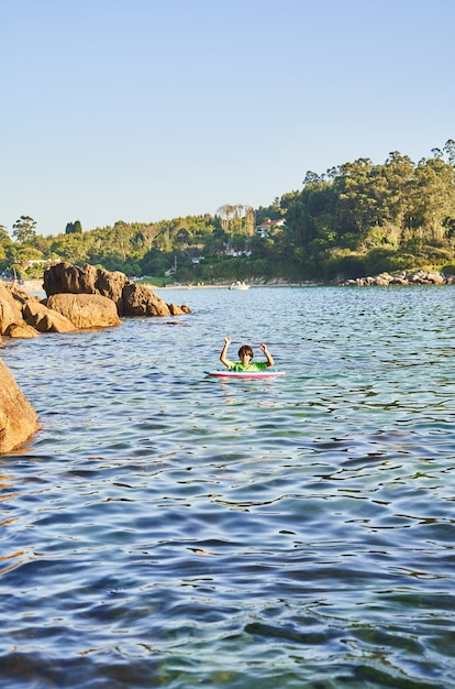 Szczęśliwe dziecko bawiące się w morzu z bodyboard. Dziecko zabawy na świeżym powietrzu. Koncepcja letnich wakacji i zdrowego stylu życia.