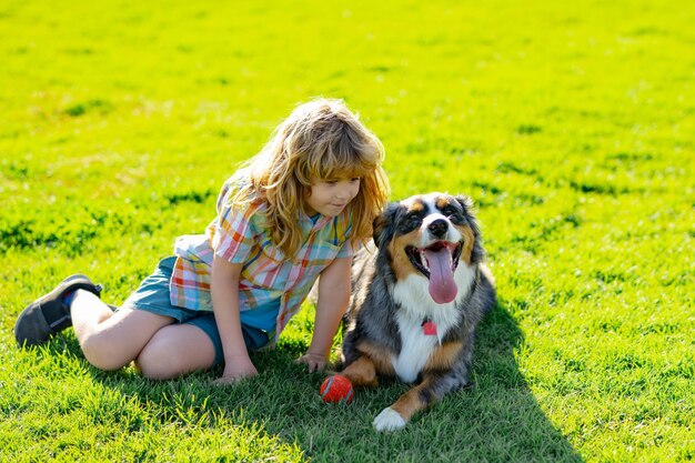 Szczęśliwe dziecko bawiące się z psem w zielonej trawie