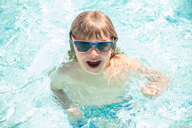 Szczęśliwe dziecko chłopiec w okularach pływanie w basenie, letnie wakacje.